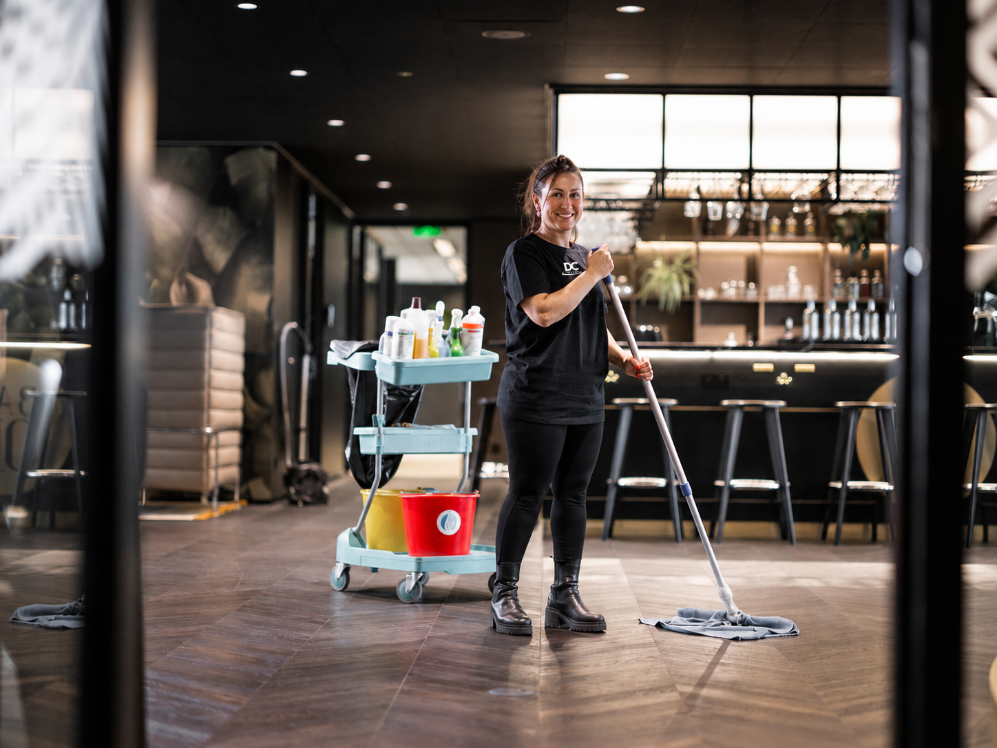 Schoonmaakmedewerker van DC Cleaning dweilt de vloer van een horecagelegenheid met schoonmaakkar